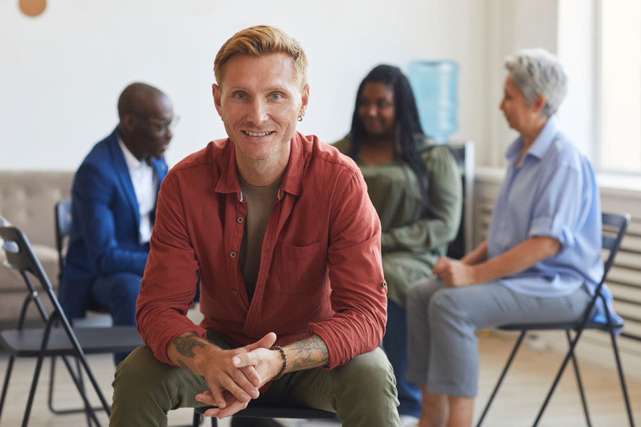 Man smile in front three peers in therapy