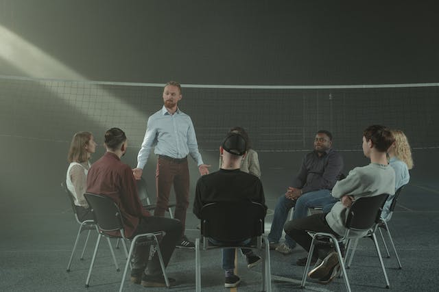 Man standing and talking in a large group therapy session